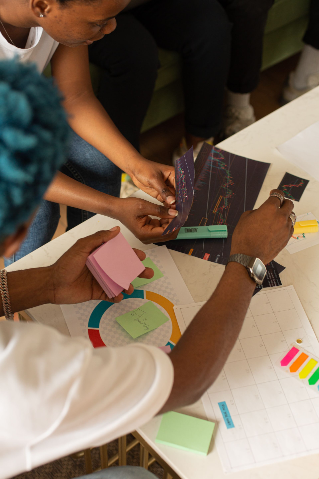 Overhead view of Black colleagues collaborating around a table covered with papers, charts and sticky notes