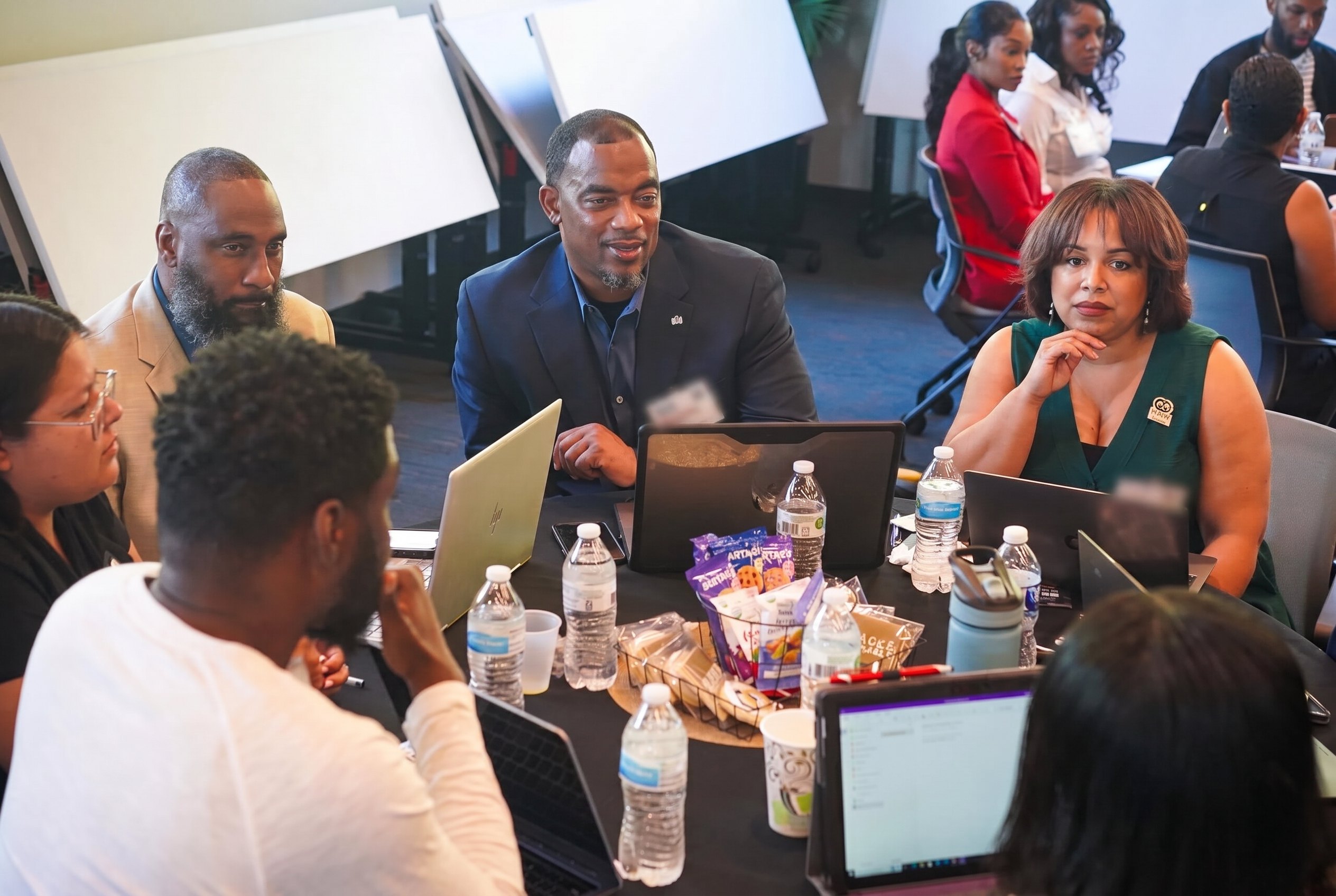 A group of Black men and women gathered around a wooden table in conversation